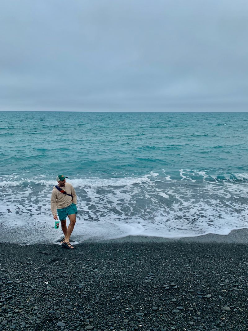 Black sand washing into cloudy Pacific infinity; a familiar bummer in the foreground utterly ruining the shot.